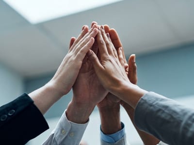 Several coworkers joining hands in a high five above an office table