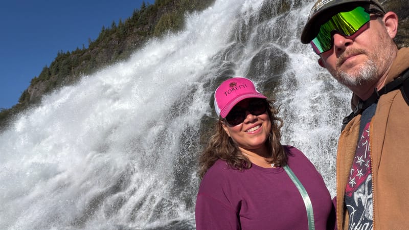 John Brandes and a companion taking a selfie in front of a rushing waterfall